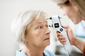 Elderly woman getting her eye's intraocular pressure measured by an ophthalmologist using a modern tonometer