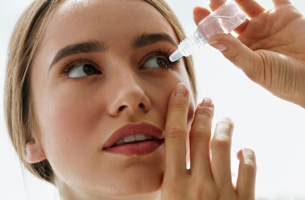 A closeup of a woman applying eye drops to help with her dry eye syndrome
