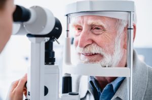 A smiling senior male patient getting an eye exam to look for glaucoma