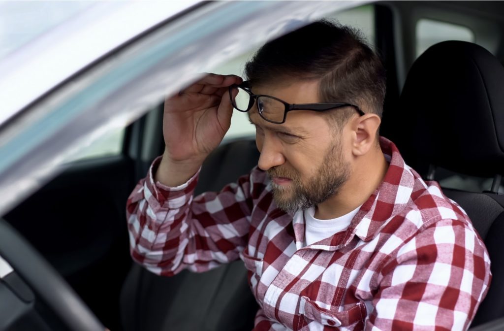 A driver with glasses suffering from blurry vision needing LASIK eye surgery to correct it