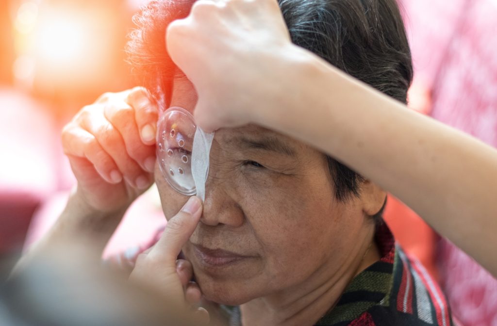 An older person getting an eyeshield positioned with tape over their right eye to protect it after cataract surgery