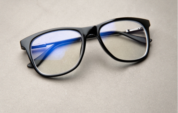 A pair of black anti-glare glasses laying on a grey surface