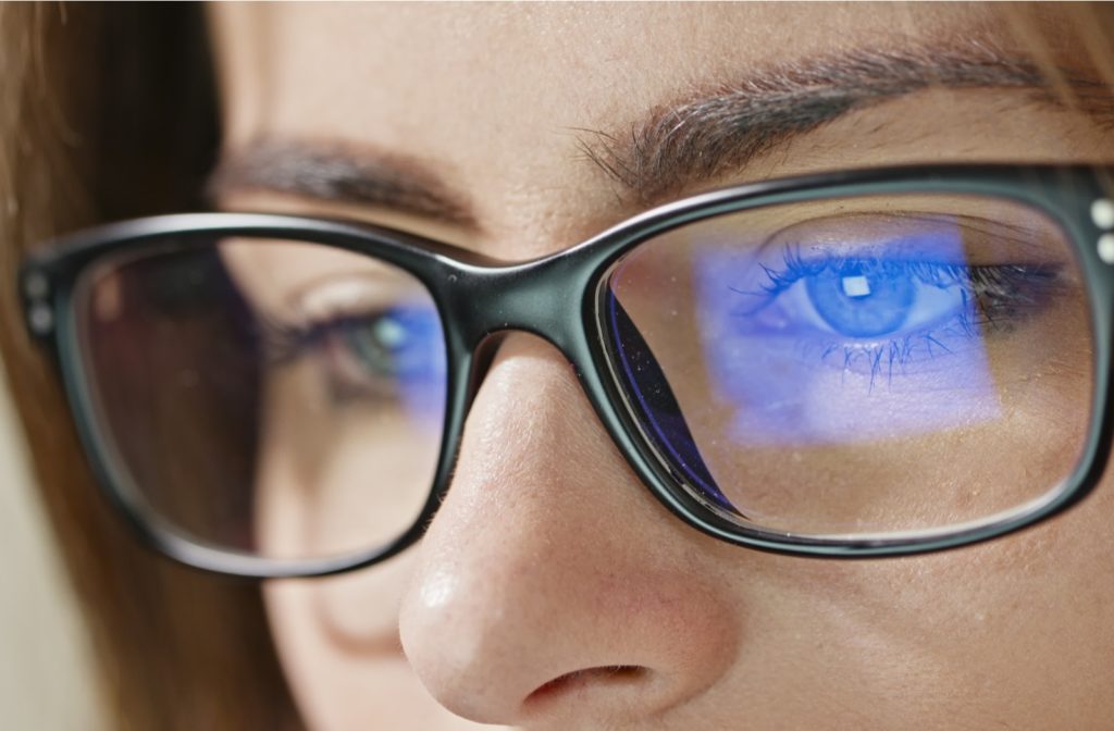 A close-up view of a woman's glasses showing her anti-glare lens cating while she's using a computer
