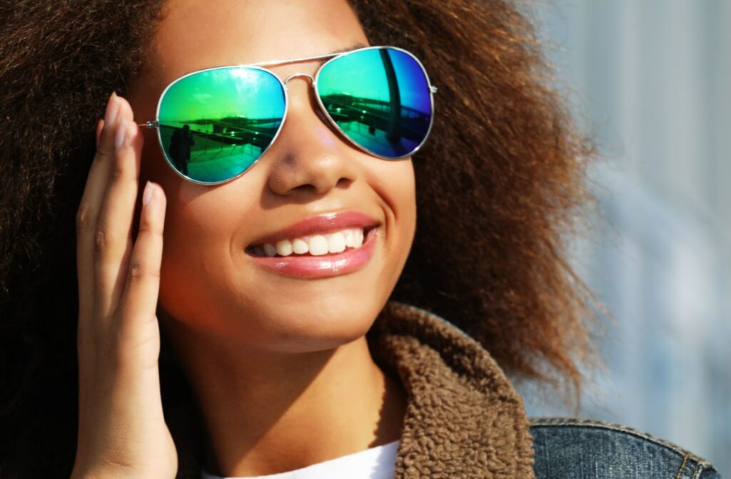A beautiful young girl in a denim jacket is wearing polarized sunglasses on a sunny day