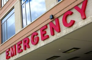Outside of an emergency room, view of a sign in red letters that spells "emergency"