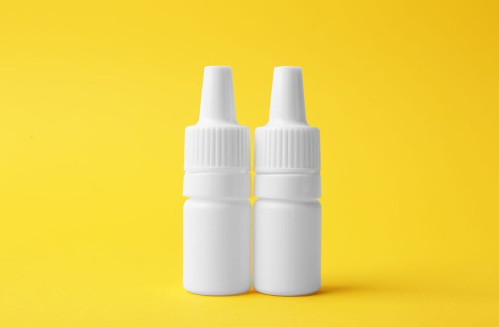 Two bottles of eye drops against a yellow background.