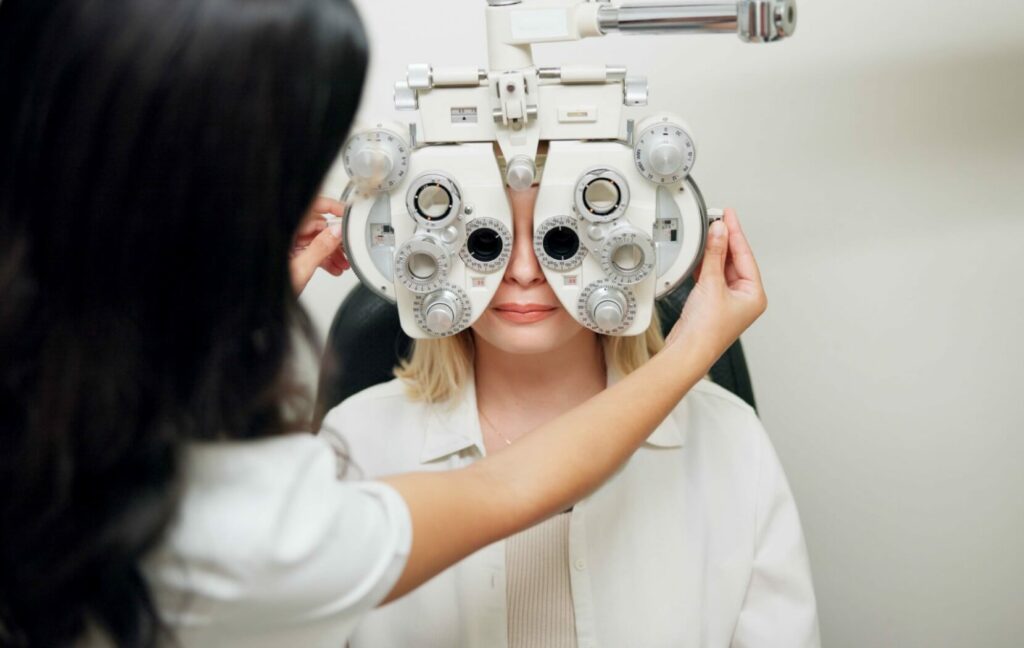 An optometrist uses a digital phoropter machine to test their patient's eye sight during a routine comprehensive eye exam.