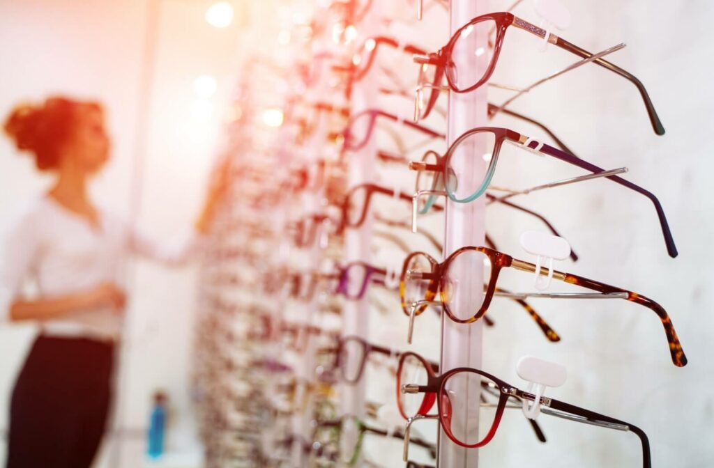 A warm lens flare illuminates a wall of stylish, trendy eyeglass frame options available at an optometrist’s