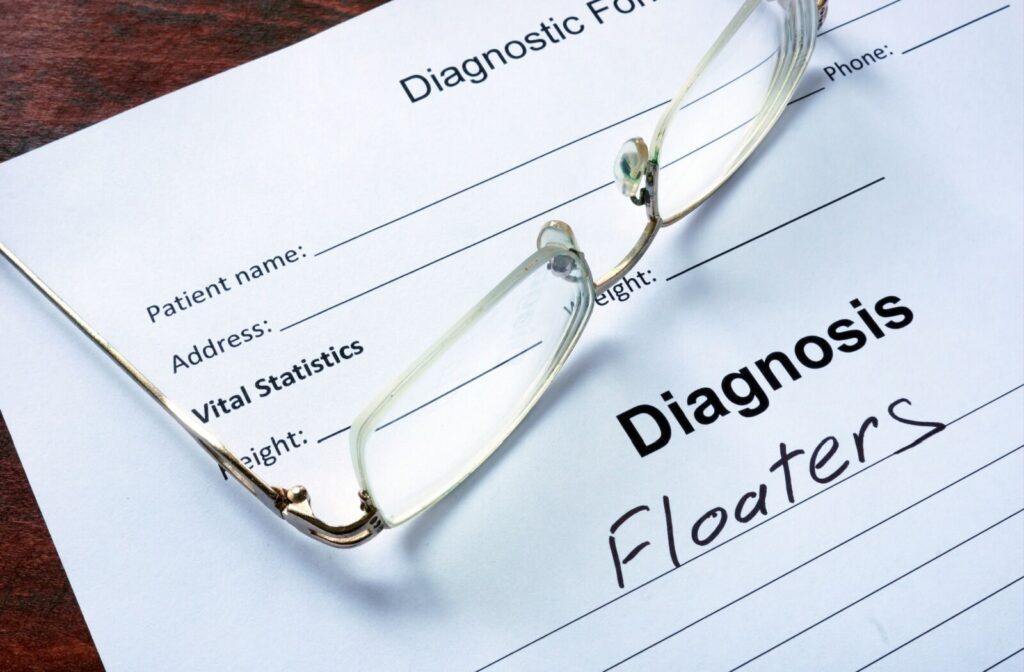 Eyeglasses resting on a paper that reads, "Diagnosis: Floaters".